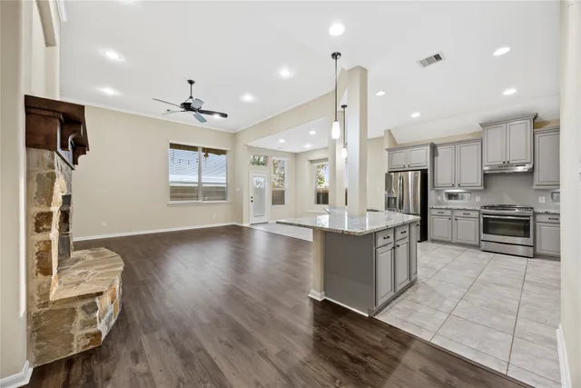 a large kitchen with stainless steel appliances kitchen island granite countertop a large stove a refrigerator a sink a dining table and chairs with wooden floor
