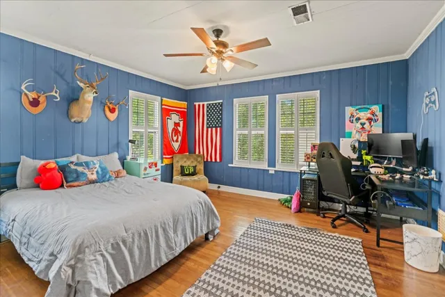 a bedroom with a bed and dresser with floor to ceiling window