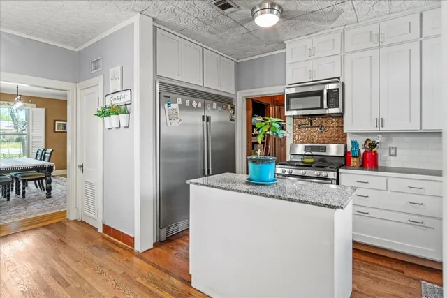a kitchen with stainless steel appliances granite countertop a refrigerator and a stove top oven