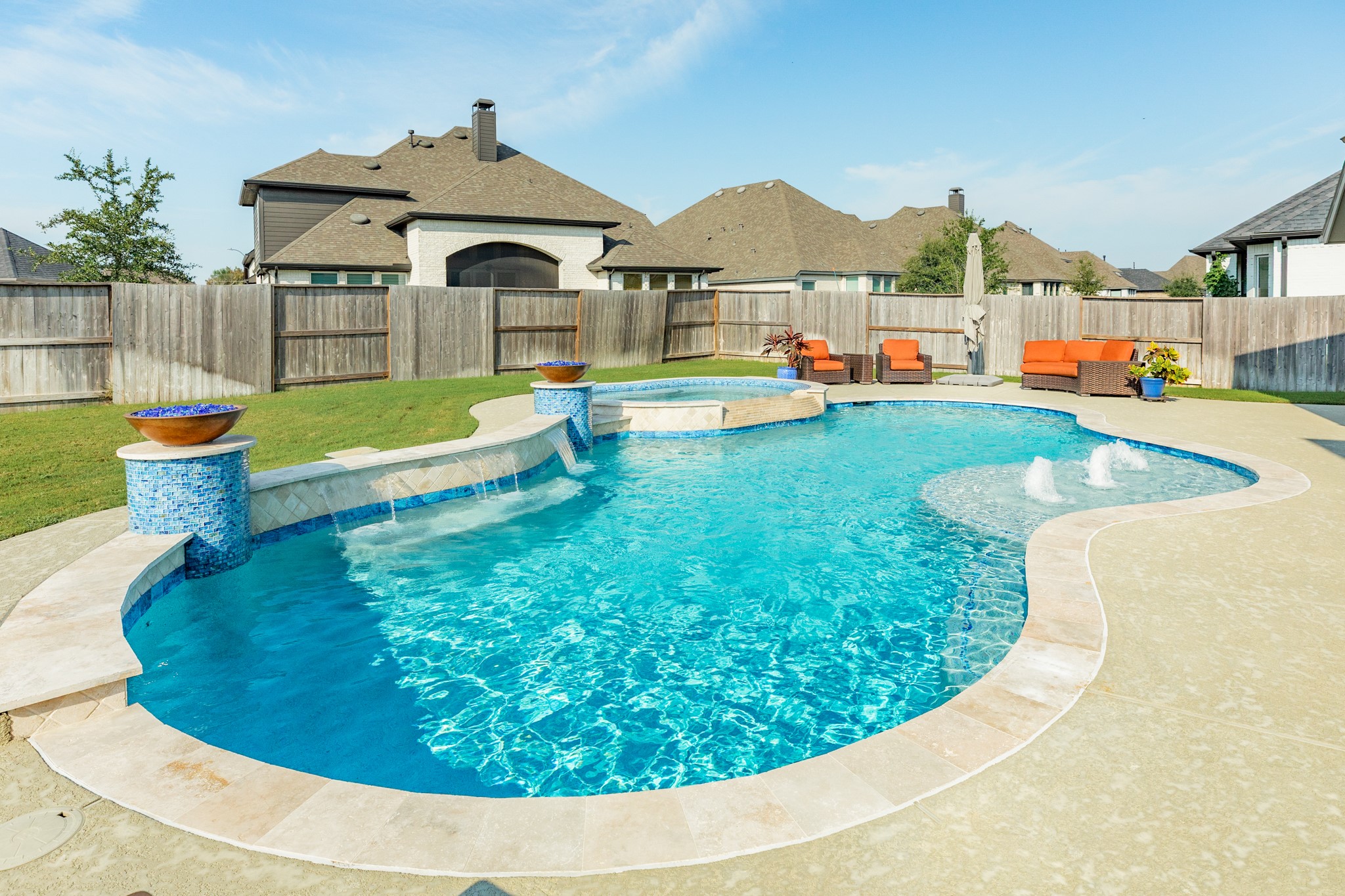 9538 Sanger Way Manvel, TX 77578 - Photo 34 of 50 Stunning outdoor oasis featuring a resort-style pool with three waterfalls, a tanning ledge with three bubblers, two fire bowls, and an oversized hot tub.