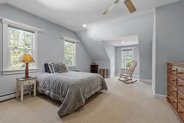 a spacious bedroom with a bed a chandelier and windows