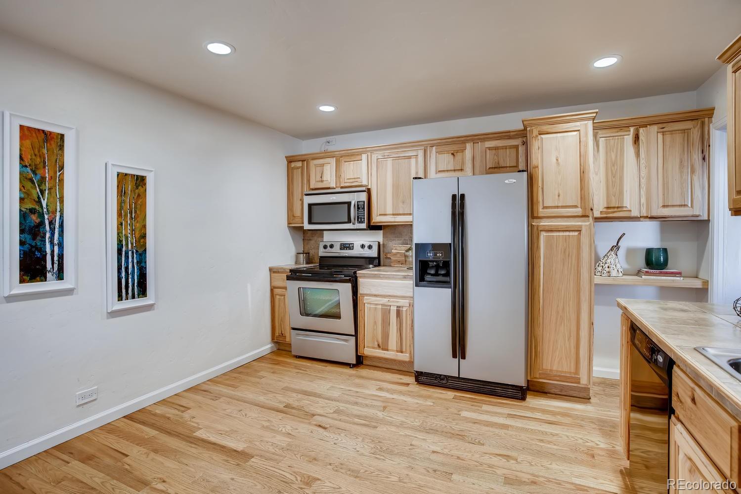 1718 South Decatur Street Denver, CO 80219 - Photo 11 of 28 a kitchen with stainless steel appliances granite countertop a refrigerator microwave and stove