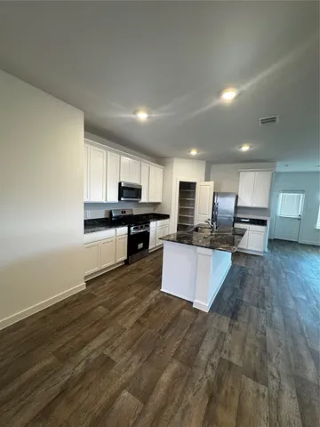 a large kitchen with kitchen island a white counter top and stainless steel appliances