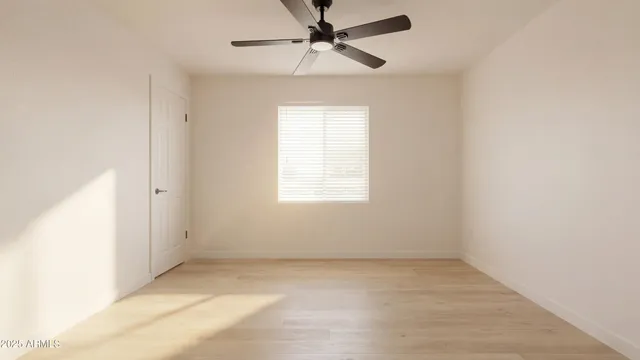 an empty room with a window and a fan
