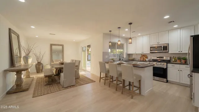 a large kitchen with kitchen island a large counter top dining table and stainless steel appliances