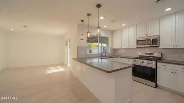 a large kitchen with stainless steel appliances granite countertop a stove a sink a oven and a refrigerator