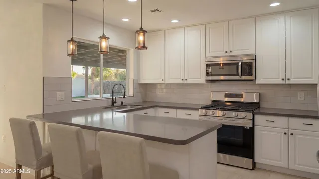 a kitchen with stainless steel appliances granite countertop a sink a stove a microwave and a refrigerator