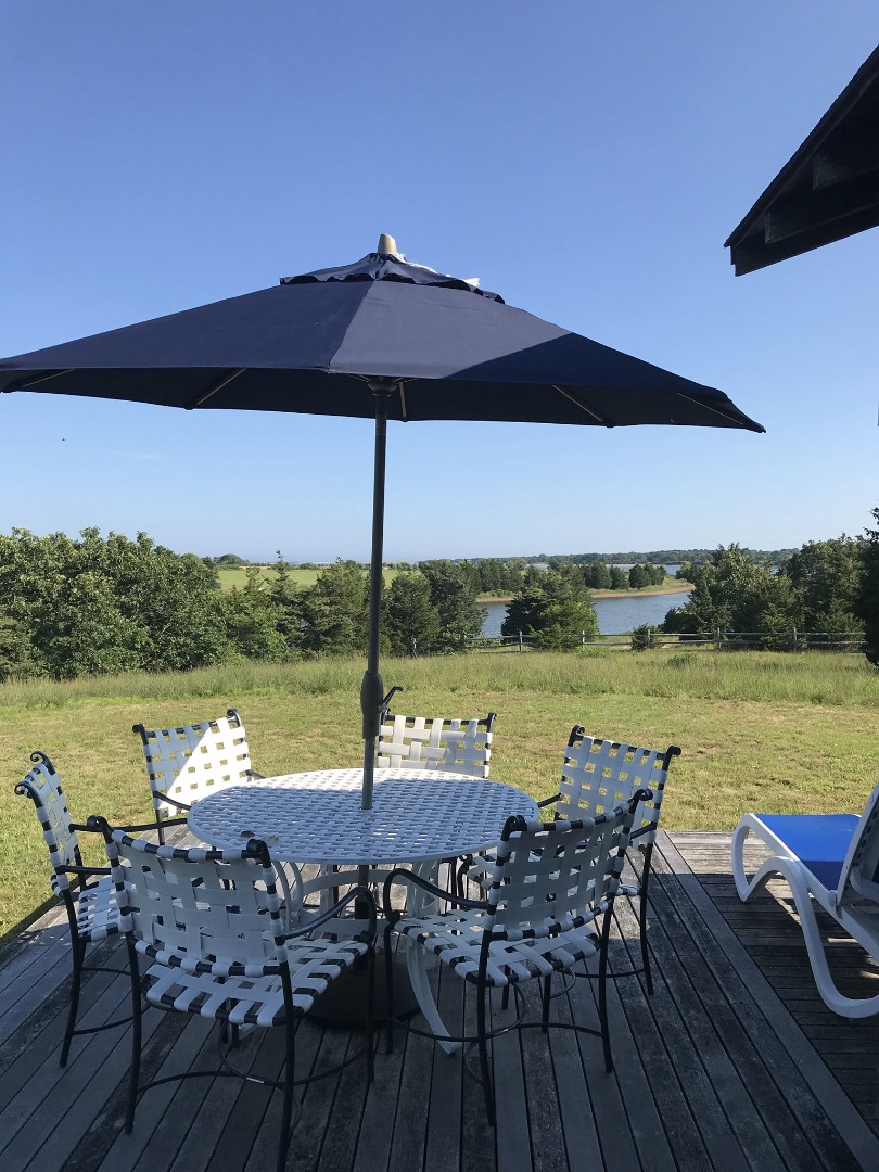 144 Pond View Farm Road West Tisbury, MA 02568 - Photo 7 of 13 a view of a lake with table and chairs under an umbrella