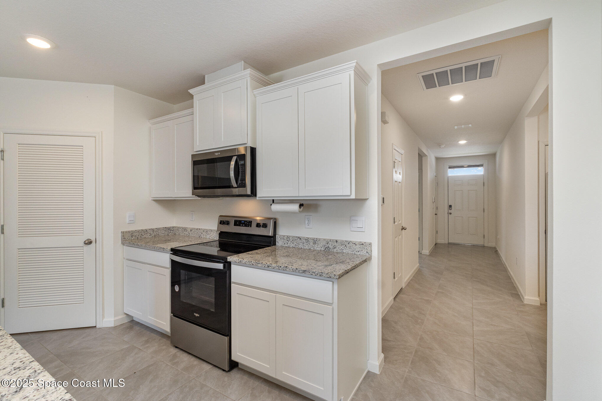 6714 Topaz Drive Grant-Valkaria, FL 32949 - Photo 7 of 33 a kitchen with granite countertop white cabinets and stainless steel appliances
