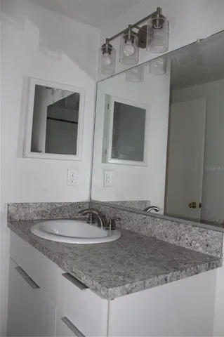 a bathroom with a granite countertop sink and a mirror