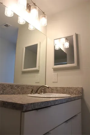 a bathroom with a granite countertop sink and a mirror