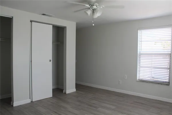 an empty room with wooden floor closet and windows