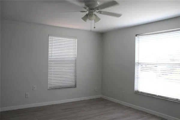 a view of an empty room with a window and wooden floor