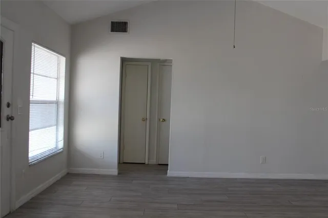 a view of an empty room with wooden floor and a window