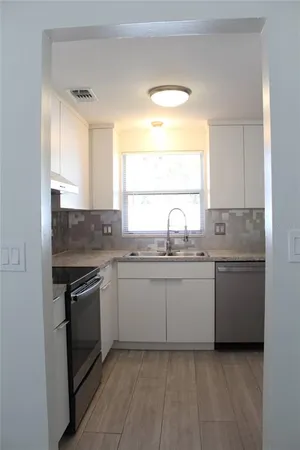 a kitchen with granite countertop cabinets stainless steel appliances a sink and a window