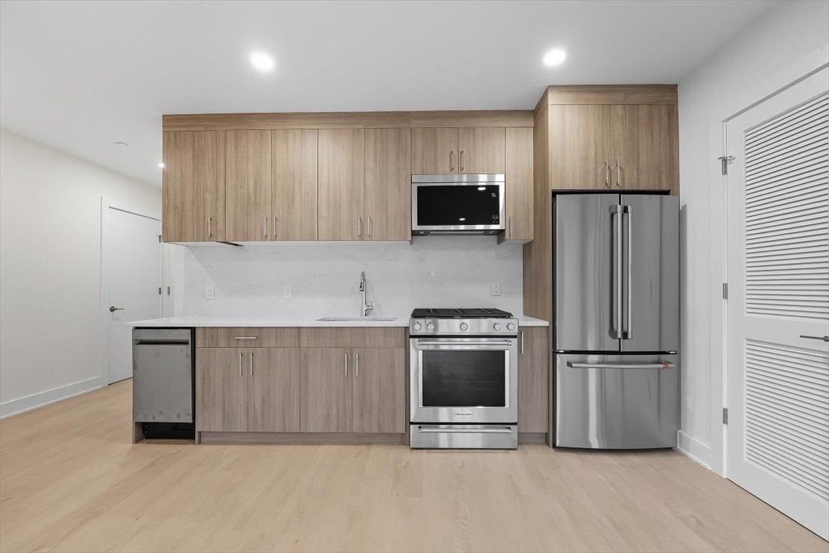 a kitchen with granite countertop a refrigerator and a stove top oven