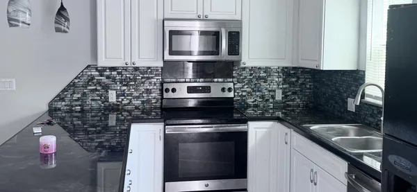 a kitchen with granite countertop a sink stove and microwave