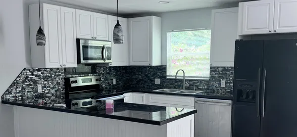 a kitchen with kitchen island granite countertop a sink a stove and a microwave