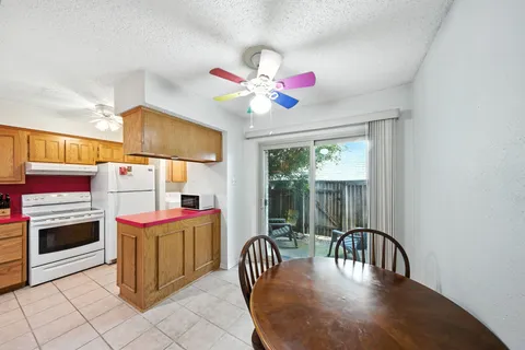 a kitchen with a stove a faucet a dining table and chairs with wooden floor
