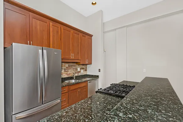 a kitchen with granite countertop a refrigerator stove and cabinets
