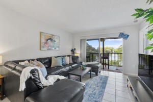 2236 North Cypress Bend Drive, Unit 311 Pompano Beach, FL 33069 - Photo 3 of 56 a living room with furniture large windows and a flat screen tv
