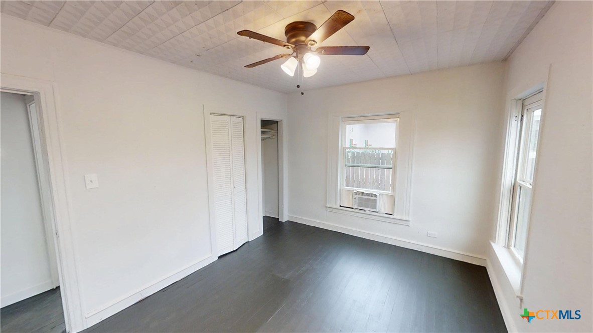 1114 South 2nd Street Temple, TX 76504 - Photo 13 of 13 an empty room with wooden floor chandelier fan and windows