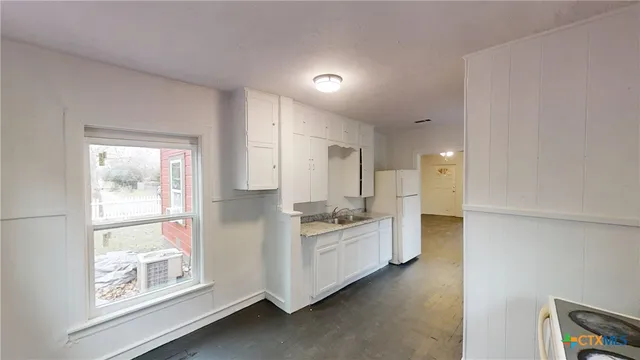 a kitchen with white cabinets and wooden floor