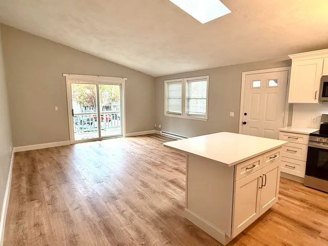 wooden kitchen with a stove a sink and white cabinets with wooden floor