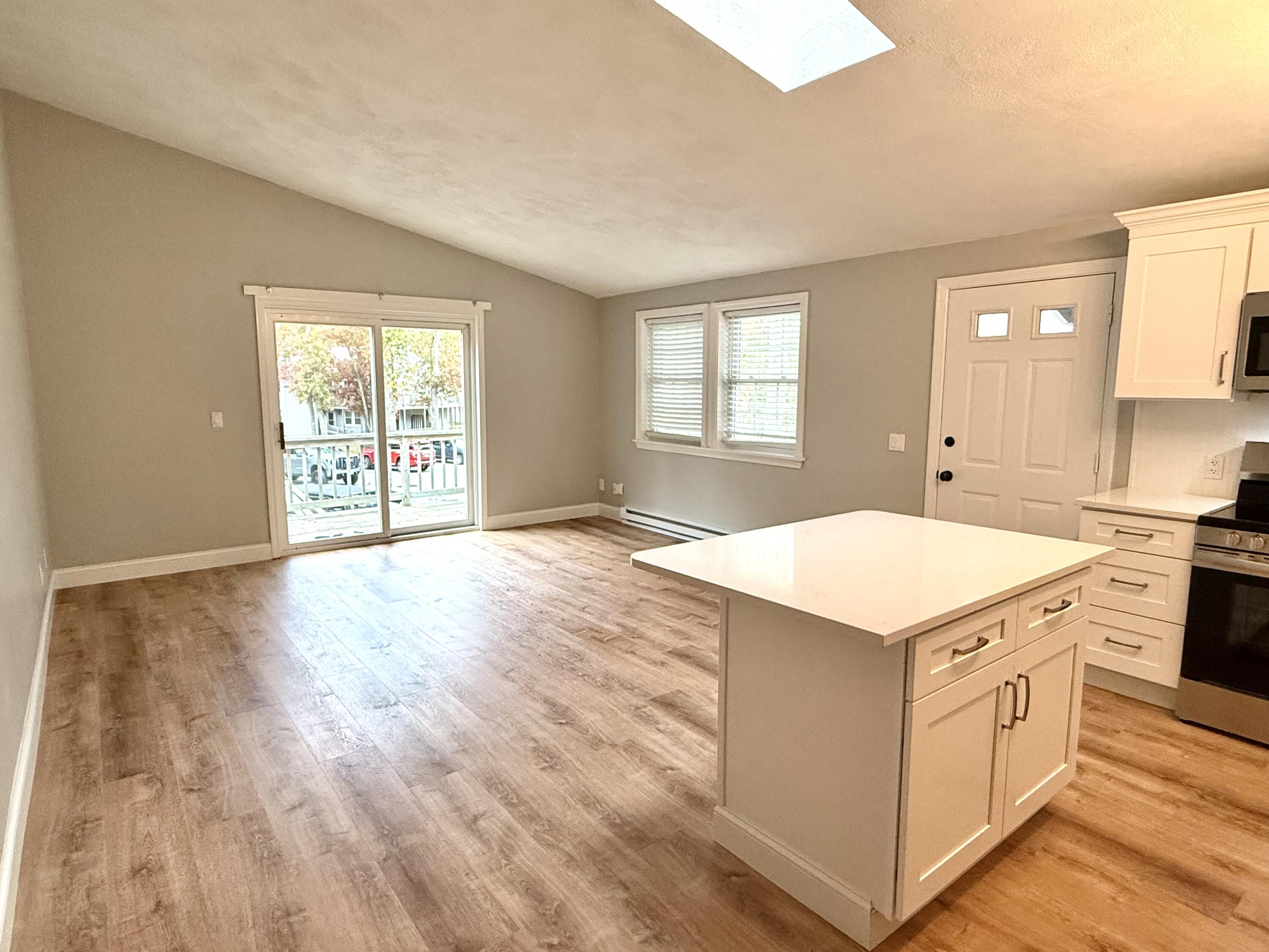 70 Cape Drive, Unit 4C Mashpee, MA 02649 - Photo 3 of 6 wooden kitchen with a stove a sink and white cabinets with wooden floor