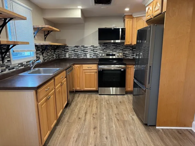 a kitchen with stainless steel appliances granite countertop a sink a stove top oven a refrigerator and a microwave