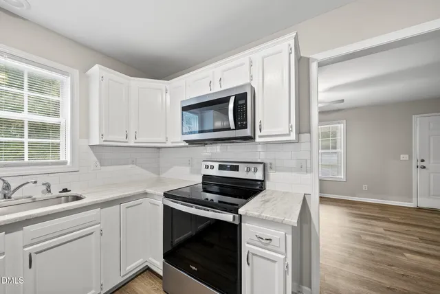 a kitchen with cabinets stainless steel appliances a sink and wooden floor