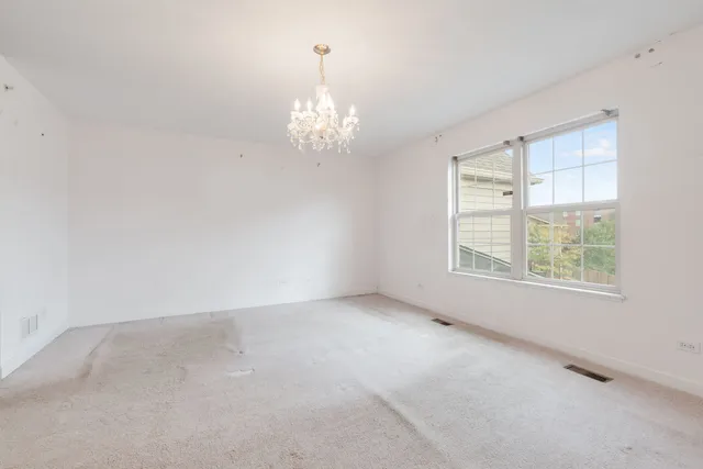 an empty room with a chandelier fan and windows