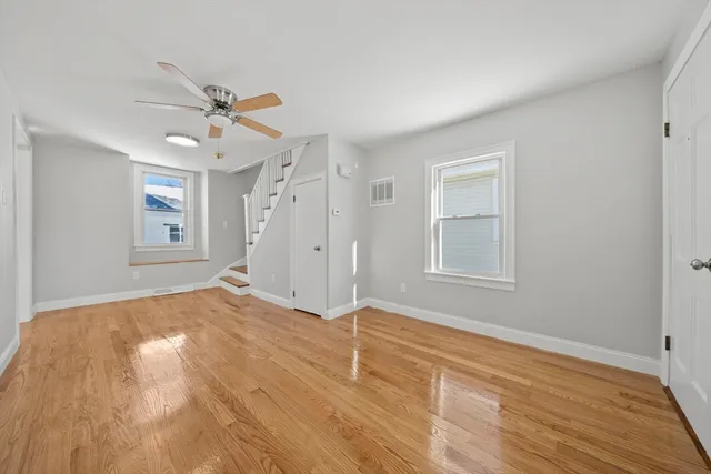 a view of empty room with wooden floor and fan