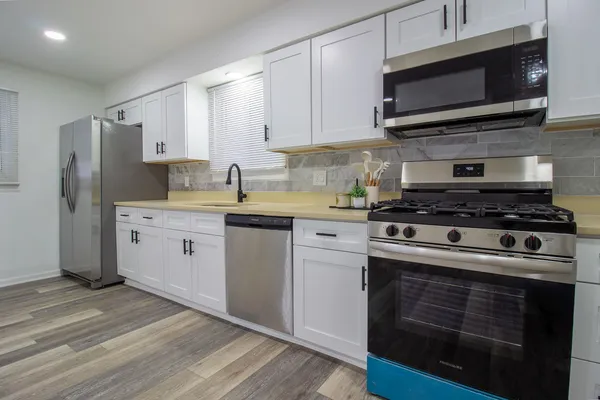 a kitchen with stainless steel appliances a stove a microwave a sink and cabinets