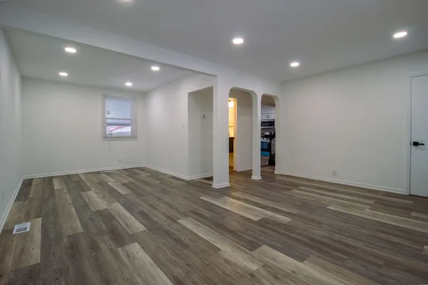 an empty room with wooden floor and window