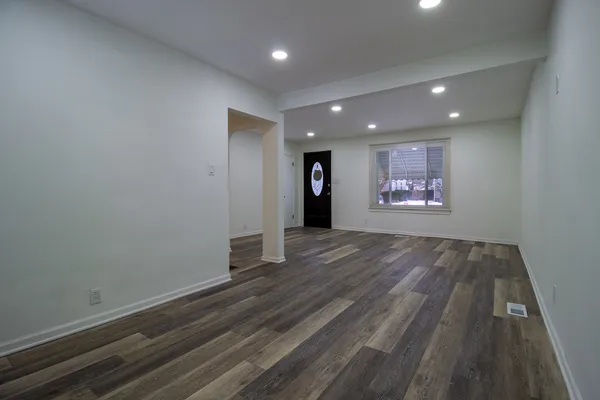 an empty room with wooden floor and windows