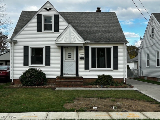 View of front of home with a chimney, a front yard, and roof with shingles
