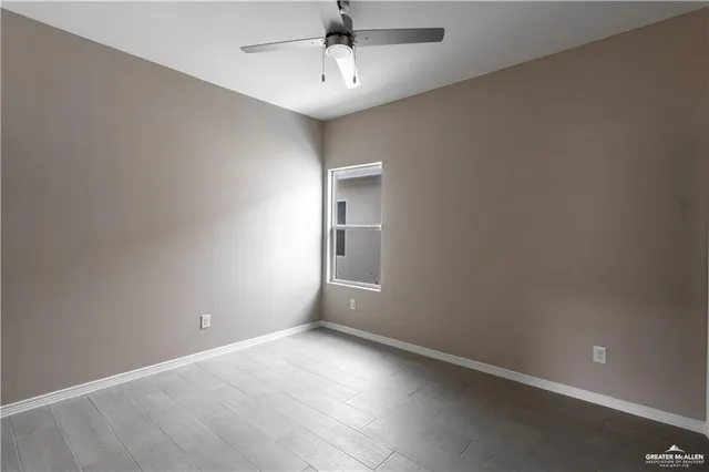 an empty room with a chandelier fan and windows
