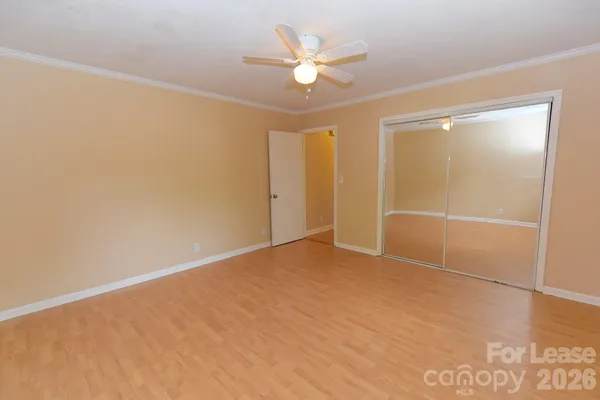 an empty room with closet and a ceiling fan