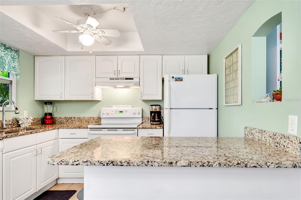 412 80th Street Holmes Beach, FL 34217 - Photo 21 of 58 a kitchen with kitchen island sink refrigerator and cabinets