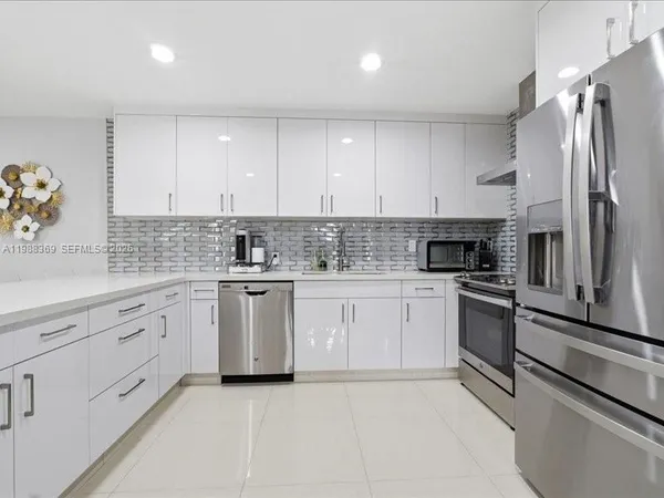 a kitchen with granite countertop white cabinets and stainless steel appliances