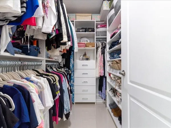 a view of walk in closet with clothes and shoes