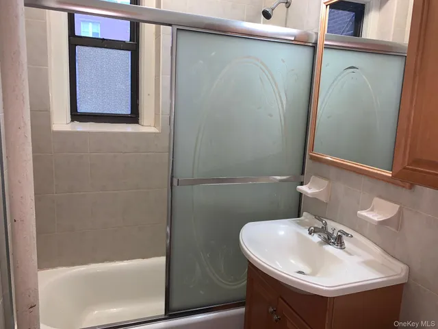 a bathroom with a sink and mirror with bathtub