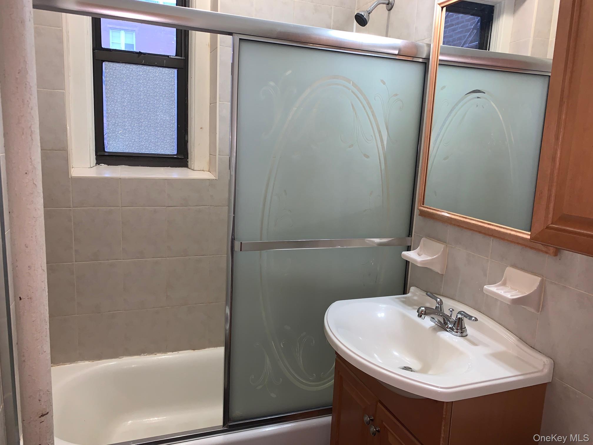 43-33 48th Street, Unit 4E Queens, NY 11104 - Photo 11 of 16 a bathroom with a sink and mirror with bathtub