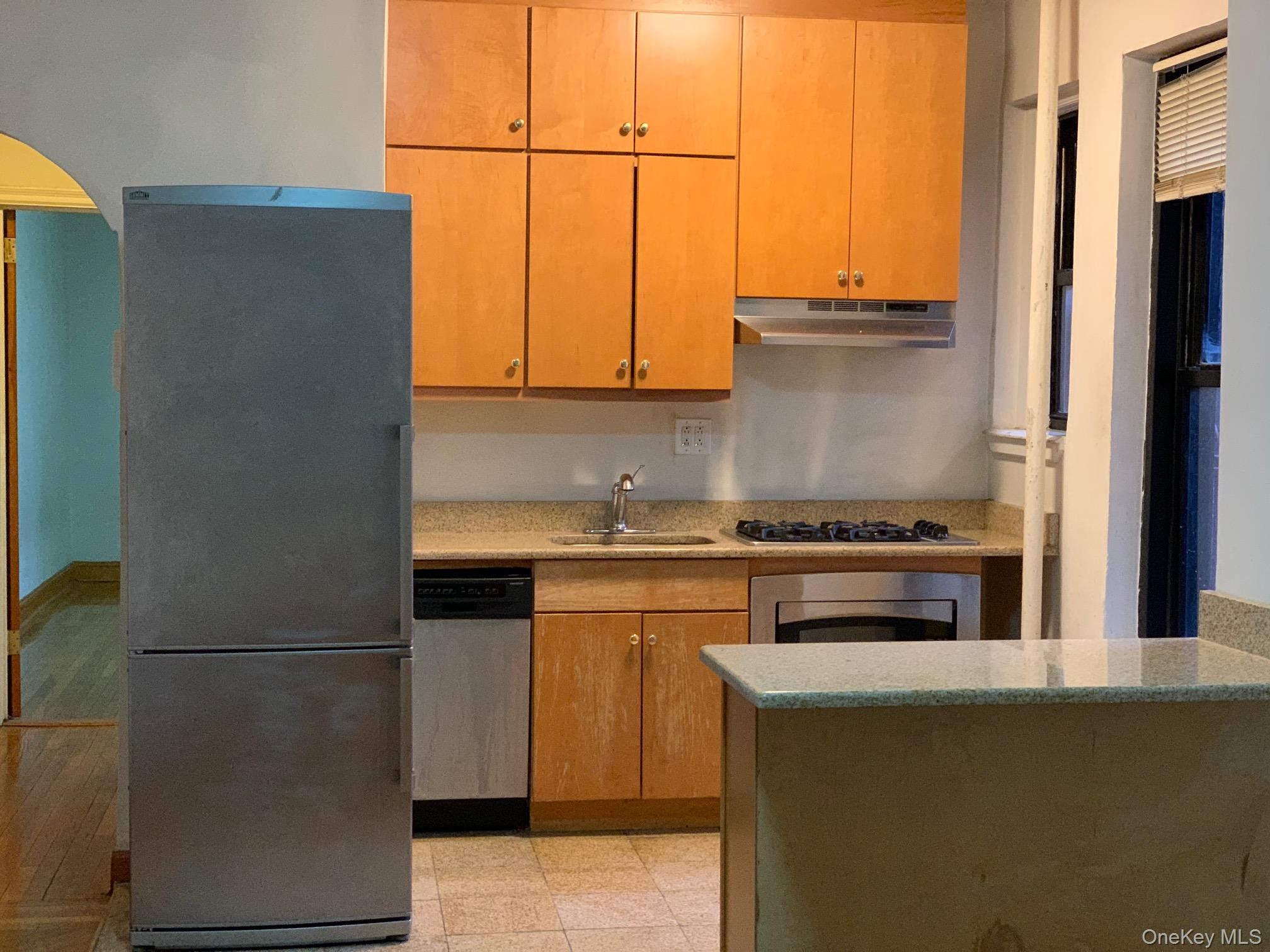 43-33 48th Street, Unit 4E Queens, NY 11104 - Photo 9 of 16 a kitchen with stainless steel appliances white cabinets and a refrigerator