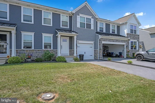 a view of a brick house with a yard and plants