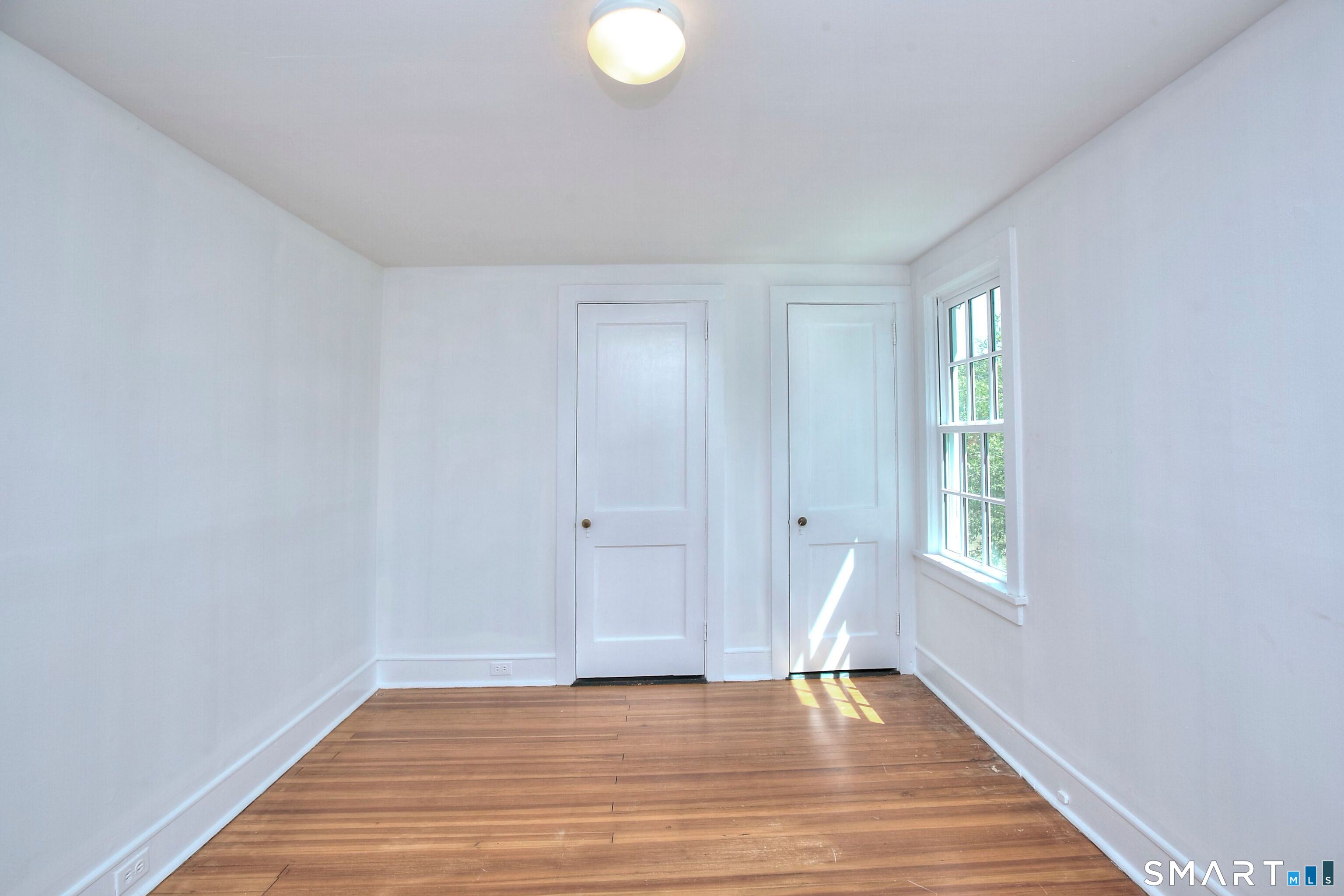 94 Honey Hill Road Wilton, CT 06897 - Photo 13 of 18 a view of an empty room with window and wooden floor
