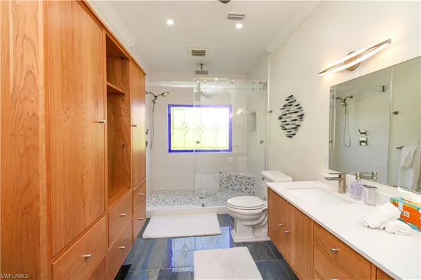 a bathroom with a double vanity sink a toilet a mirror and shower