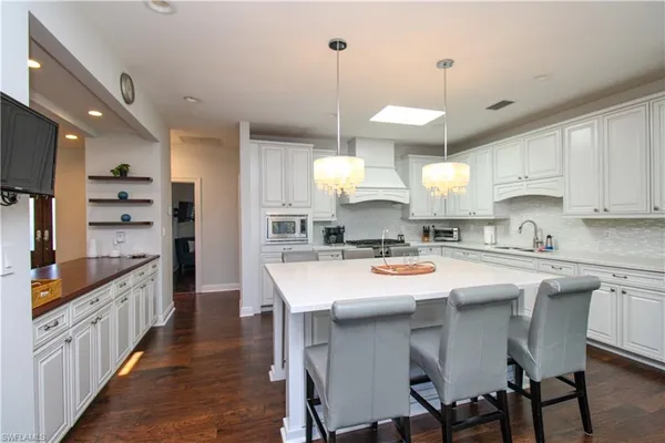 a kitchen with stainless steel appliances a stove a sink a refrigerator and chairs