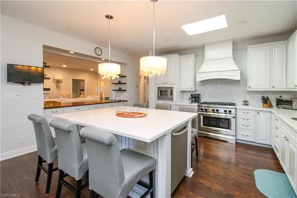 a kitchen with a stove a sink a kitchen island with chairs and wooden floor
